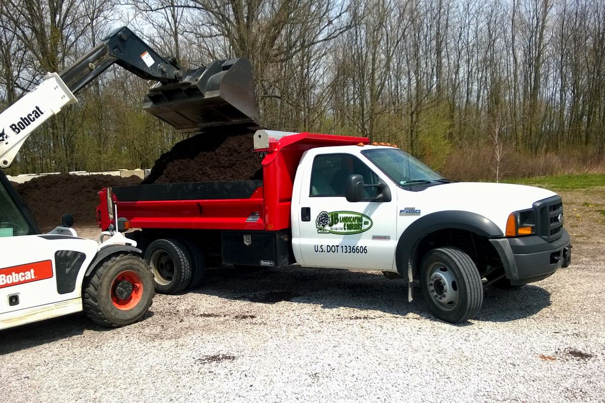 JB Landscape & Nursery dump truck being loaded with mulch by a Bobcat at the State Rd 9 yard